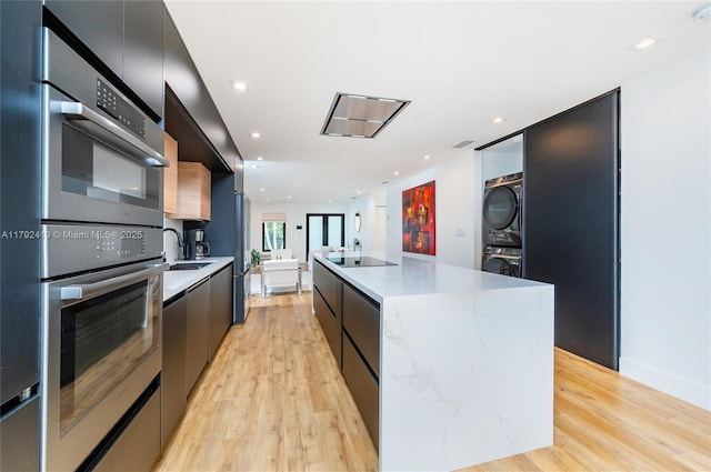 kitchen featuring a center island, modern cabinets, stacked washer / drying machine, and light wood-type flooring