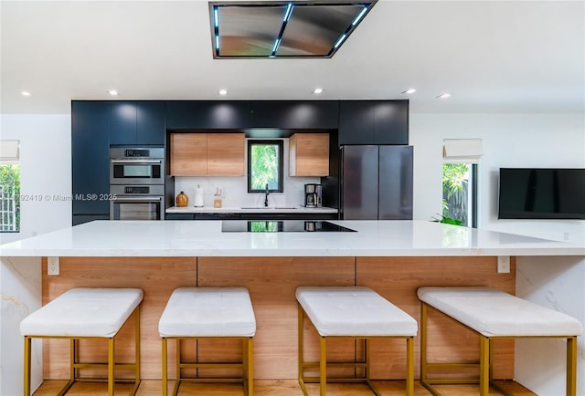kitchen featuring light countertops, a sink, black appliances, and modern cabinets