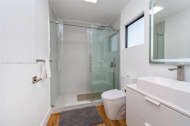 bathroom with vanity, a shower stall, toilet, and wood finished floors