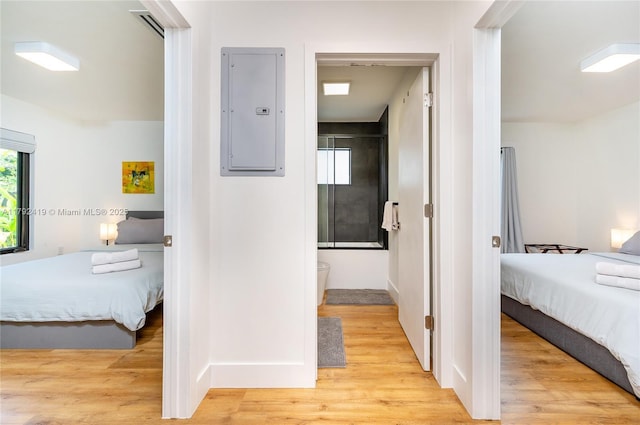 hallway featuring light wood-type flooring, baseboards, and electric panel