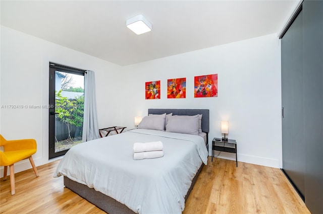 bedroom featuring access to outside, baseboards, and light wood finished floors