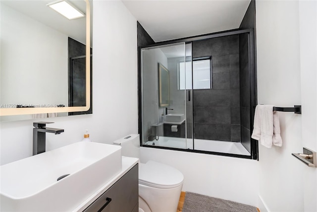 full bathroom featuring vanity, enclosed tub / shower combo, and toilet