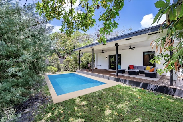 outdoor pool with a ceiling fan, a wooden deck, a fenced backyard, a yard, and outdoor lounge area
