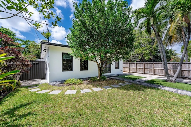 rear view of property with fence, stucco siding, and a yard