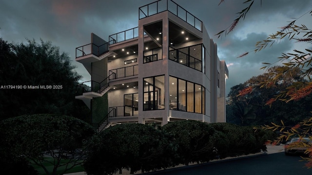 property exterior at night featuring a balcony and stucco siding