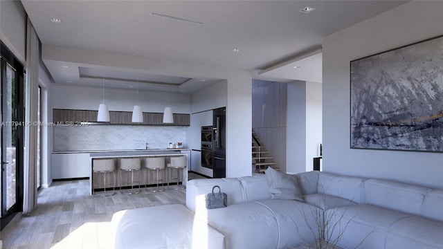 living area featuring stairs, visible vents, a raised ceiling, and light wood-style floors