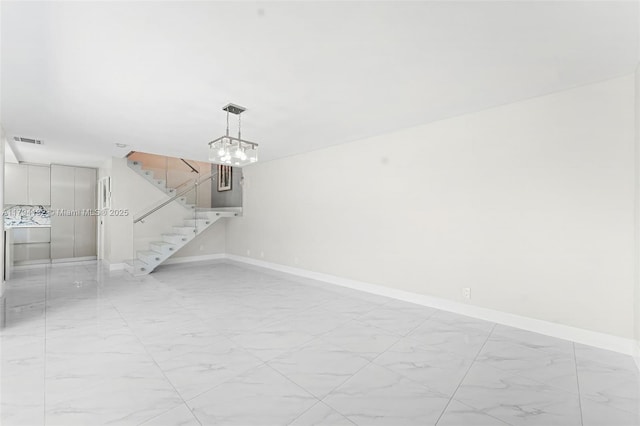 spare room with visible vents, marble finish floor, stairs, baseboards, and a notable chandelier