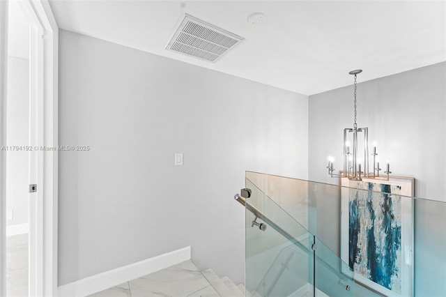 stairs with a notable chandelier, visible vents, baseboards, and marble finish floor