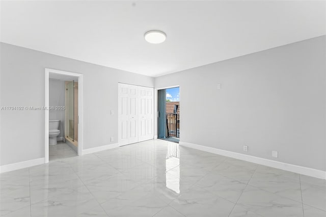 unfurnished bedroom with a closet, baseboards, marble finish floor, and ensuite bath
