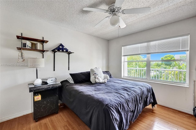 bedroom with a textured ceiling, baseboards, ceiling fan, and wood finished floors