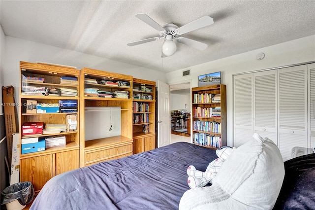 bedroom with a textured ceiling, visible vents, ceiling fan, and a closet