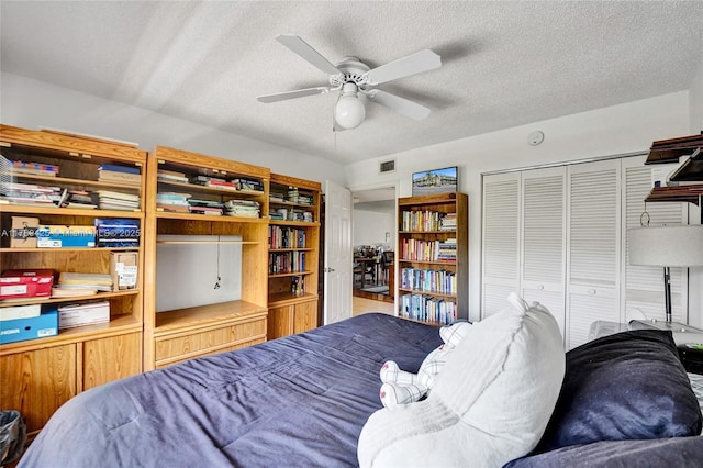 bedroom with a textured ceiling, visible vents, ceiling fan, and a closet