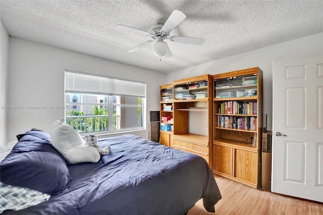 bedroom with a textured ceiling, a ceiling fan, and light wood-style flooring