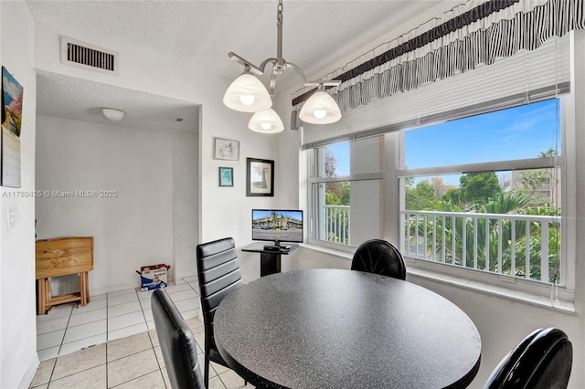 dining area with a textured ceiling, visible vents, and tile patterned flooring