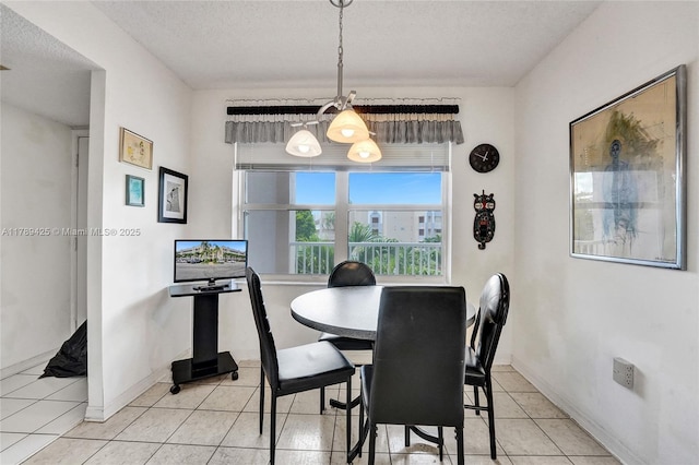 dining room with light tile patterned floors, baseboards, a textured ceiling, and a notable chandelier