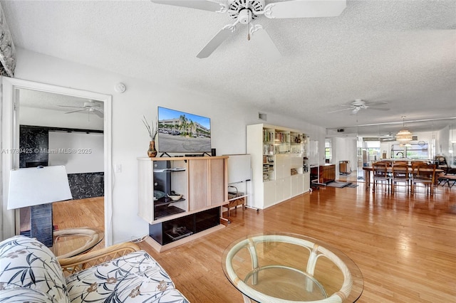 living room with a ceiling fan, a textured ceiling, and wood finished floors
