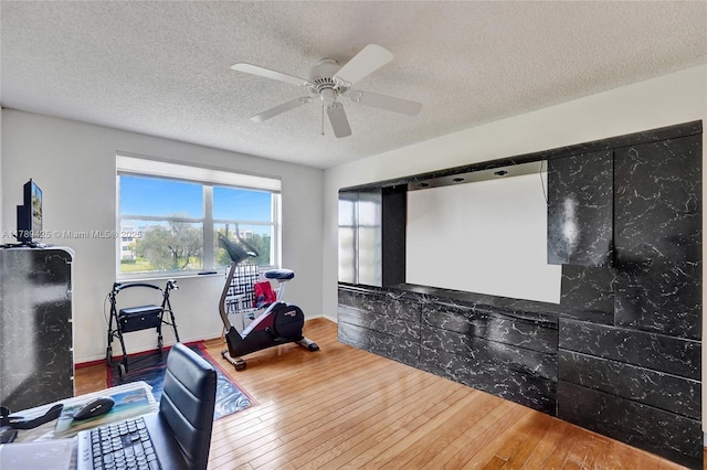 workout area featuring a textured ceiling, a ceiling fan, and hardwood / wood-style floors