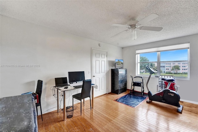 office area featuring a ceiling fan, a textured ceiling, baseboards, and hardwood / wood-style flooring