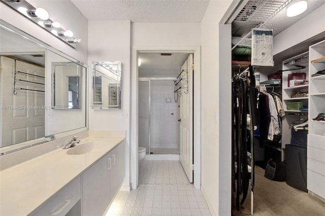 full bath with vanity, tile patterned flooring, toilet, a spacious closet, and a stall shower