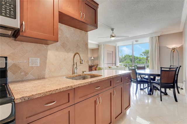 kitchen featuring light stone countertops, ornamental molding, a sink, and tasteful backsplash