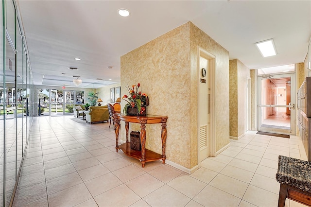 corridor with baseboards and light tile patterned flooring