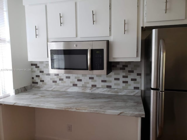 kitchen featuring white cabinets, tasteful backsplash, and stainless steel appliances