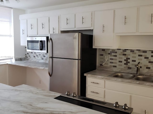 kitchen with light countertops, a sink, appliances with stainless steel finishes, and tasteful backsplash