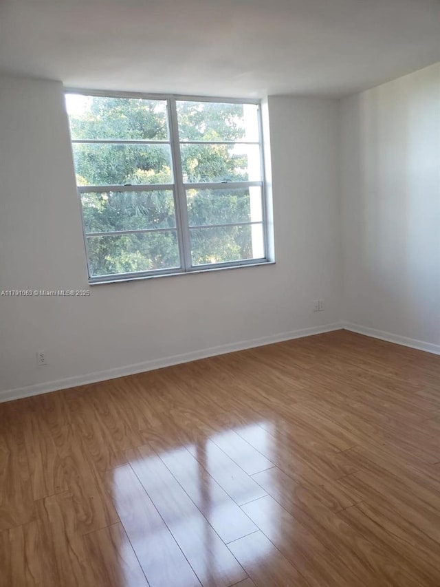 spare room featuring baseboards and wood finished floors