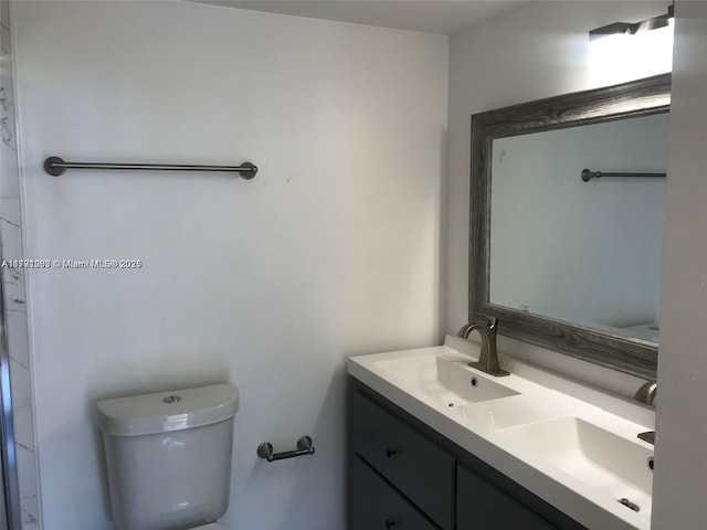 bathroom featuring double vanity, a sink, and toilet