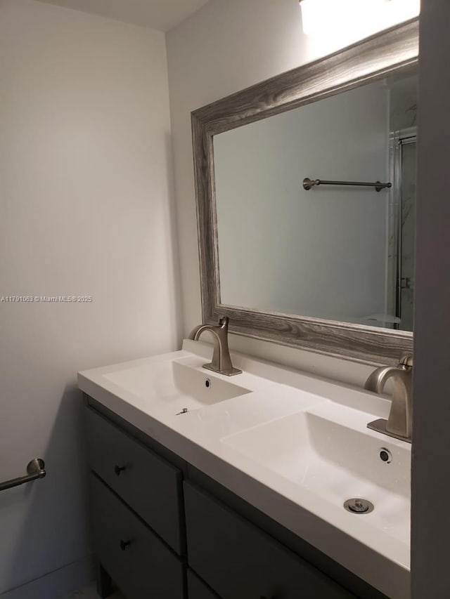 full bath with double vanity, a shower with shower door, and a sink