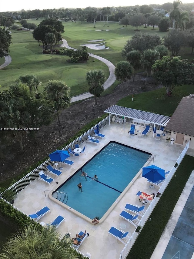 community pool featuring fence, view of golf course, and a patio area