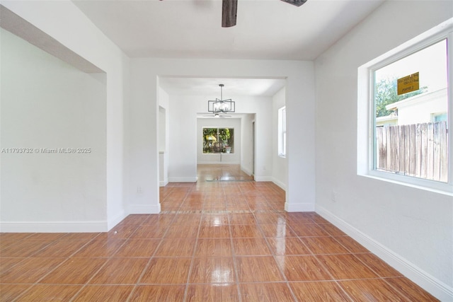 foyer entrance with baseboards and ceiling fan with notable chandelier