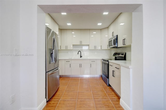 kitchen with appliances with stainless steel finishes, a sink, light countertops, decorative backsplash, and modern cabinets