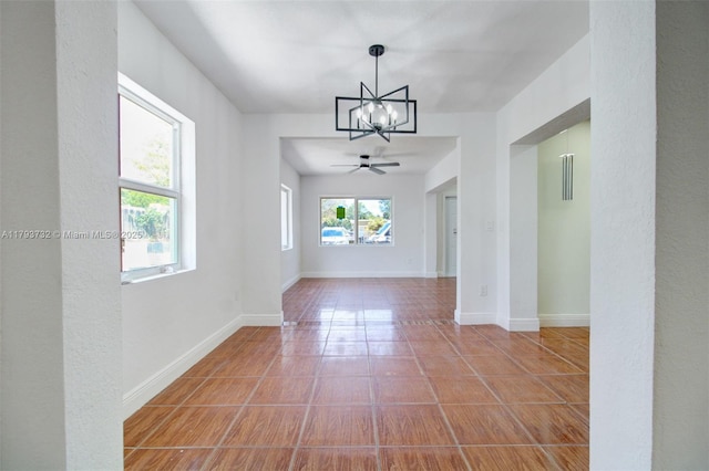 unfurnished dining area with baseboards and ceiling fan with notable chandelier