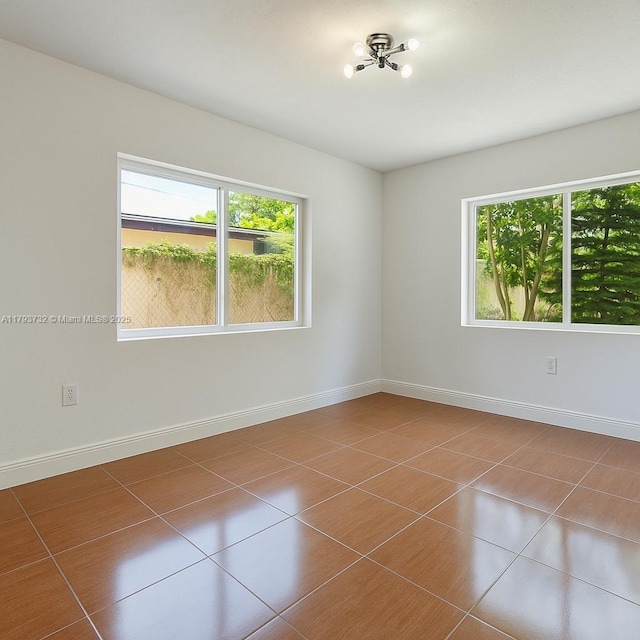 unfurnished room with baseboards, tile patterned flooring, and a wealth of natural light