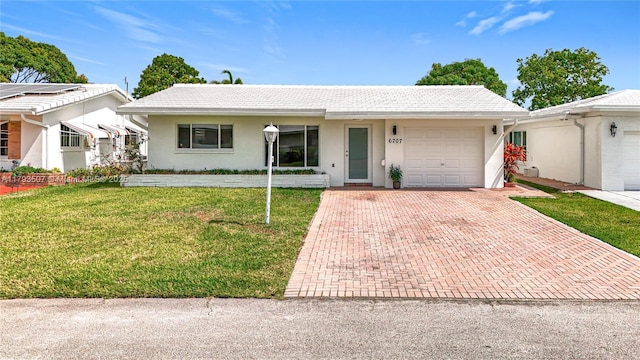 single story home featuring an attached garage, decorative driveway, stucco siding, and a front yard