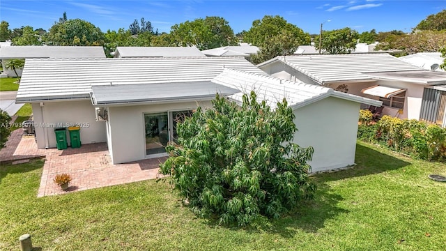 rear view of house with a lawn, a patio, and stucco siding