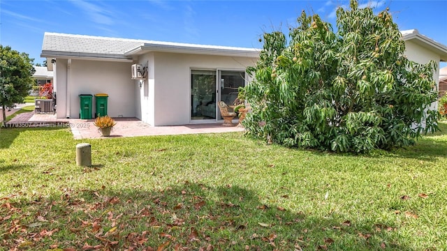 back of property featuring a lawn, a patio, central AC, and stucco siding