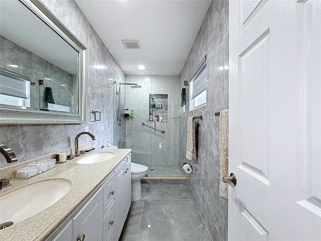 full bath featuring double vanity, a sink, a stall shower, and toilet