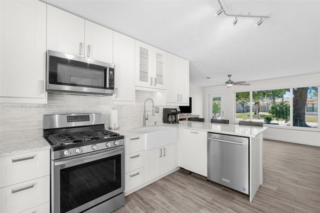 1531 NE 32nd St, Pompano Beach, FL 33064 - kitchen with a peninsula, appliances with stainless steel finishes, a sink, and tasteful backsplash