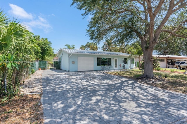 1531 NE 32nd St, Pompano Beach, FL 33064 - ranch-style house with a garage, fence, decorative driveway, stucco siding, and metal roof