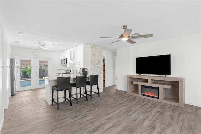 1531 NE 32nd St, Pompano Beach, FL 33064 - living area with visible vents, a glass covered fireplace, ceiling fan, french doors, and light wood-style flooring