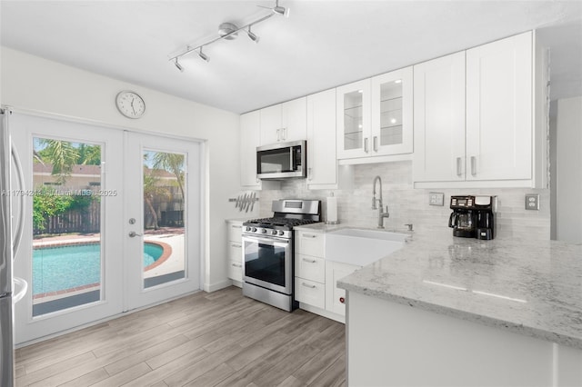 1531 NE 32nd St, Pompano Beach, FL 33064 - kitchen featuring light stone counters, appliances with stainless steel finishes, french doors, and tasteful backsplash