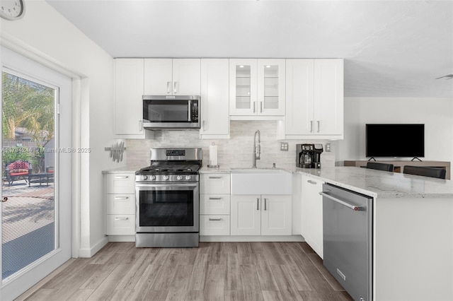 1531 NE 32nd St, Pompano Beach, FL 33064 - kitchen featuring appliances with stainless steel finishes, light stone counters, a sink, light wood-style flooring, and backsplash