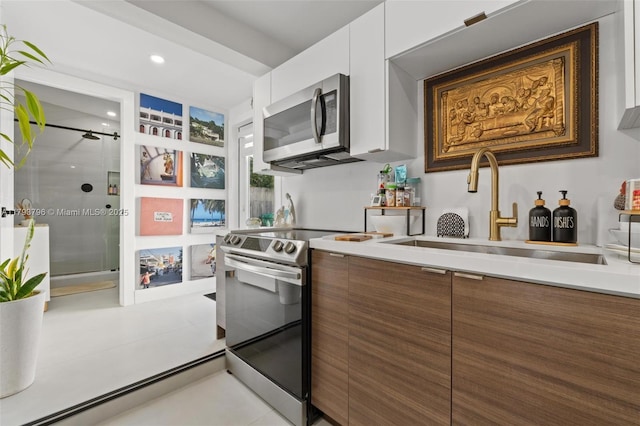 kitchen featuring modern cabinets, a sink, light countertops, white cabinets, and stainless steel appliances