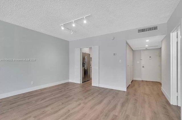 5401 Collins Ave Unit 411, Miami Beach, FL 33140 - empty room with visible vents, a textured ceiling, light wood-style flooring, and baseboards