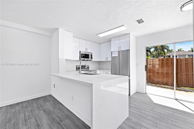 2917 NW Belmont Ln Unit 2917, Cooper City, FL 33026 - kitchen with visible vents, a peninsula, light wood finished floors, and appliances with stainless steel finishes