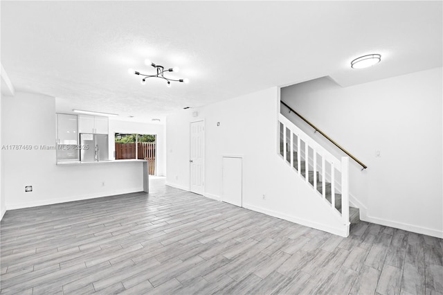 2917 NW Belmont Ln Unit 2917, Cooper City, FL 33026 - unfurnished living room with stairs, a textured ceiling, baseboards, and wood finished floors