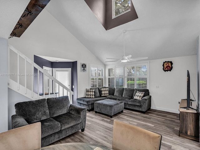 living area with stairs, wood finished floors, a wealth of natural light, and high vaulted ceiling