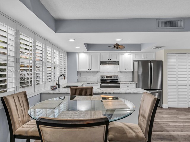 8109 Oakton Ct Unit 9D, Lake Clarke Shores, FL 33406 - kitchen featuring stainless steel appliances, a sink, under cabinet range hood, white cabinetry, and light stone counters